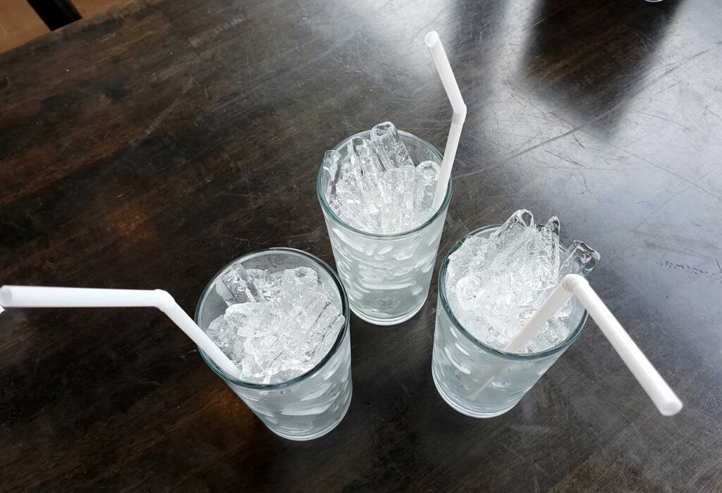 the glasses with water and ice and straws